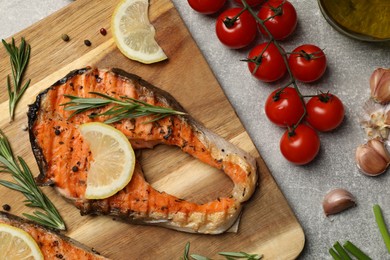 Photo of Tasty grilled salmon steak and different ingredients on light grey table, flat lay