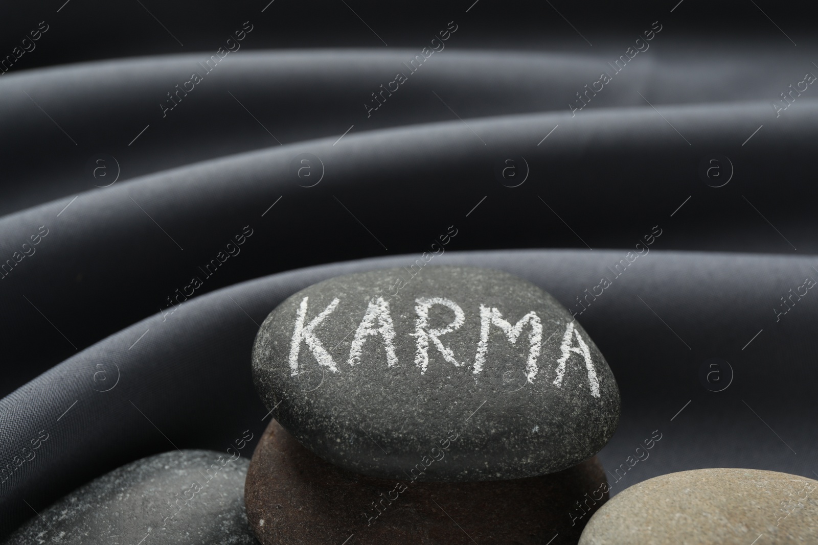 Photo of Stones with word Karma on grey fabric, closeup