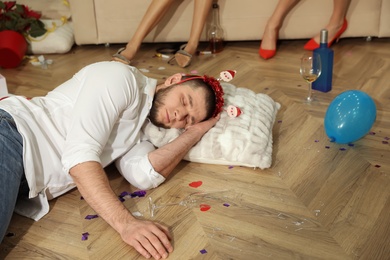 Photo of Man sleeping on floor in messy room after New Year party