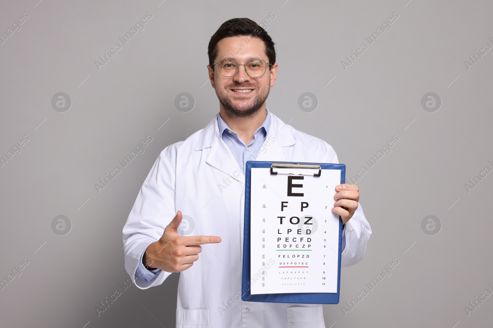 Photo of Ophthalmologist pointing at vision test chart on gray background