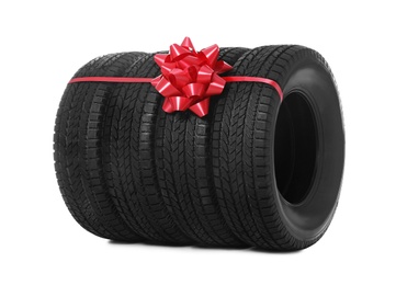 Photo of Winter tires with red ribbon on white background