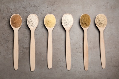 Photo of Spoons with different types of flour on table, top view