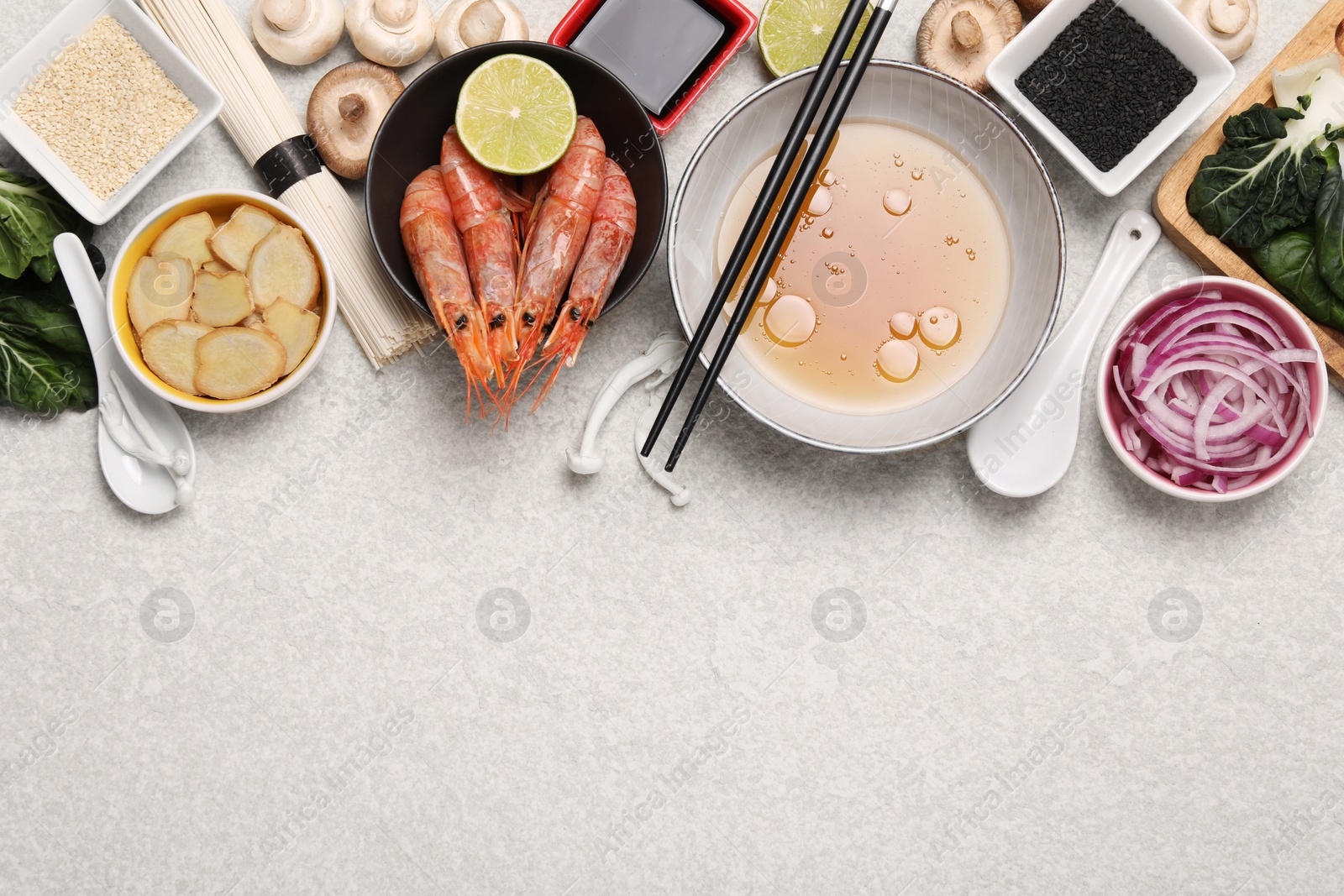 Photo of Cooking delicious ramen soup. Different ingredients on beige table, flat lay. Space for text