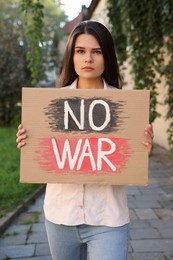 Photo of Sad woman holding poster with words No War outdoors