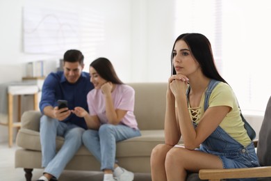 Unhappy woman feeling jealous while couple spending time together at home