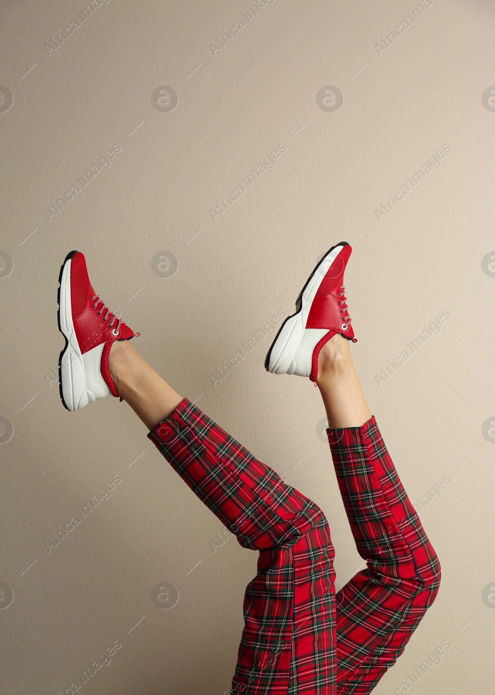 Photo of Woman wearing sneakers on beige background, closeup