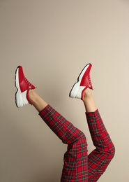 Woman wearing sneakers on beige background, closeup