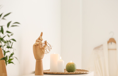 Photo of Wooden holder with jewelry and burning candles on white table in bathroom