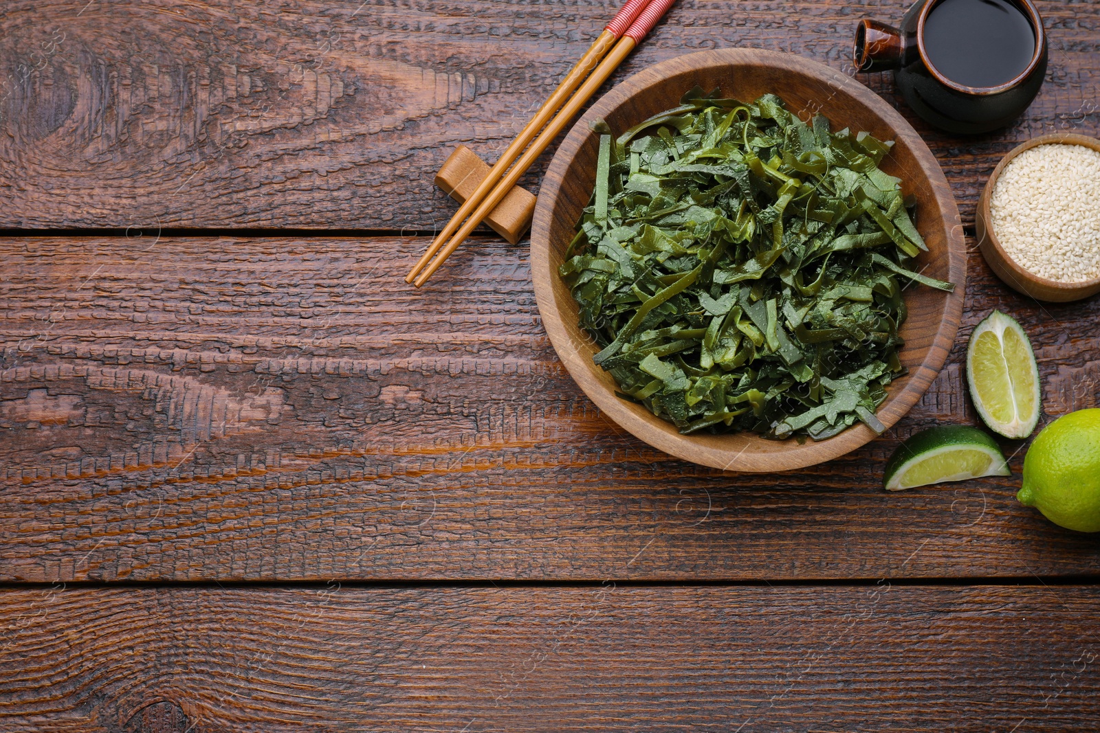 Photo of Fresh laminaria (kelp) seaweed served on wooden table, flat lay. Space for text