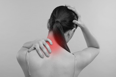 Woman suffering from neck pain on grey background, black and white effect