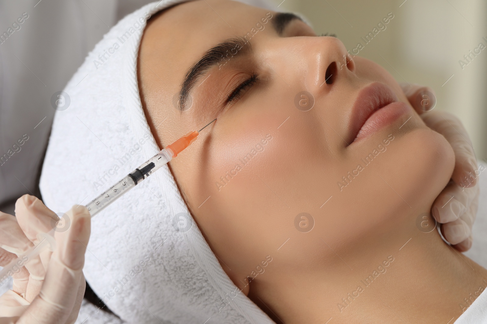 Photo of Doctor giving facial injection to young woman in clinic, closeup. Cosmetic surgery