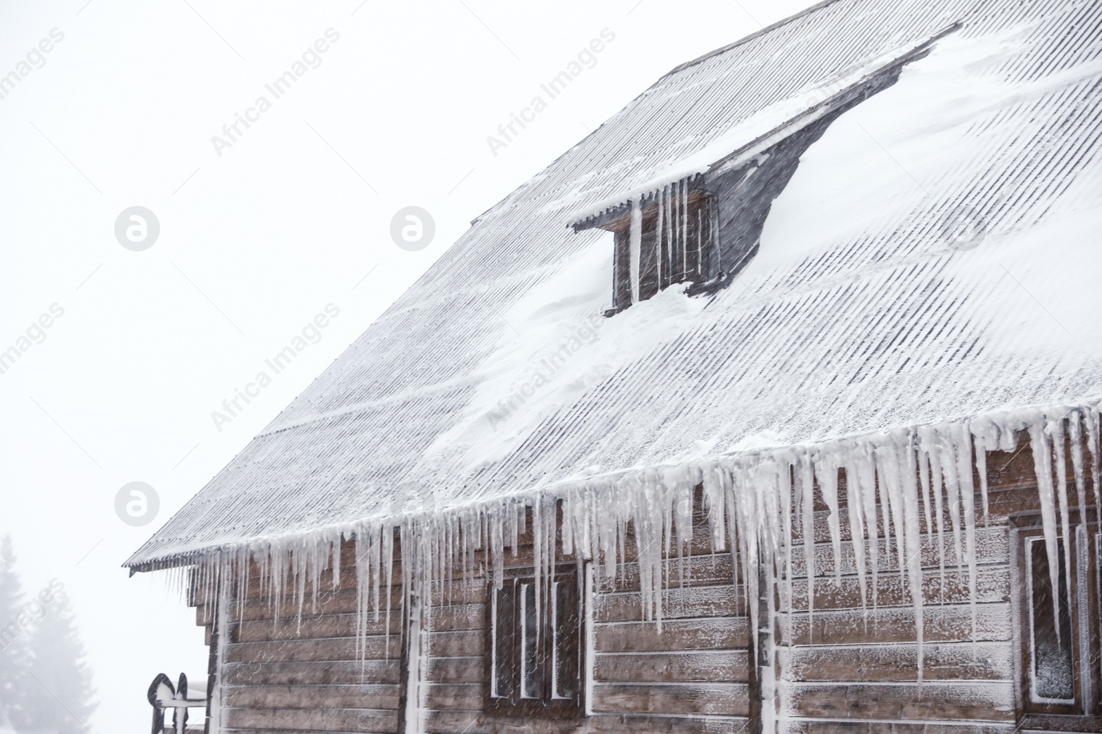 Photo of Wooden house with icicles on snowy day. Winter vacation