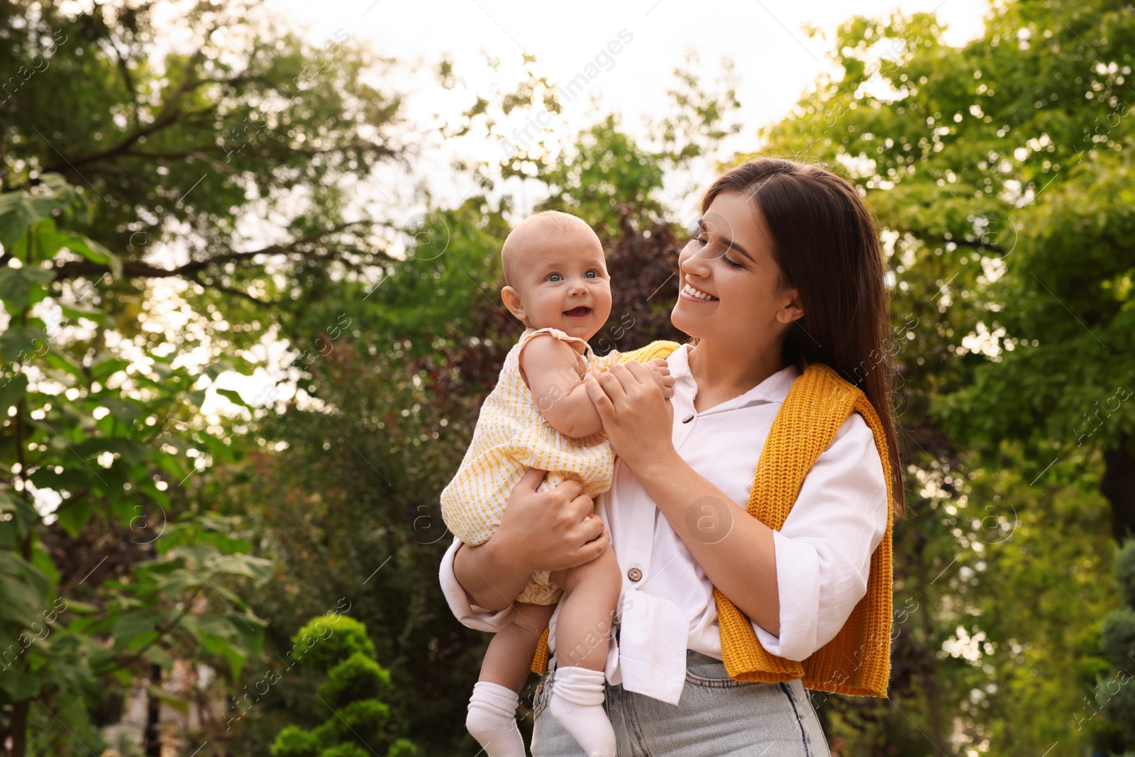 Photo of Happy mother with adorable baby walking in park on sunny day, space for text