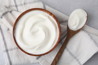 Photo of Delicious natural yogurt in bowl and spoon on light grey table, top view