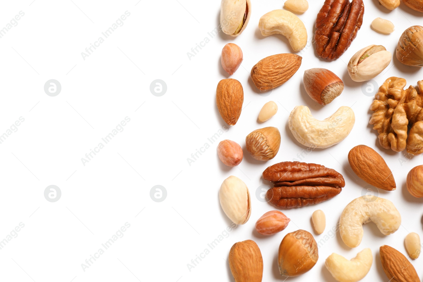 Photo of Different delicious nuts on white background, flat lay. Space for text