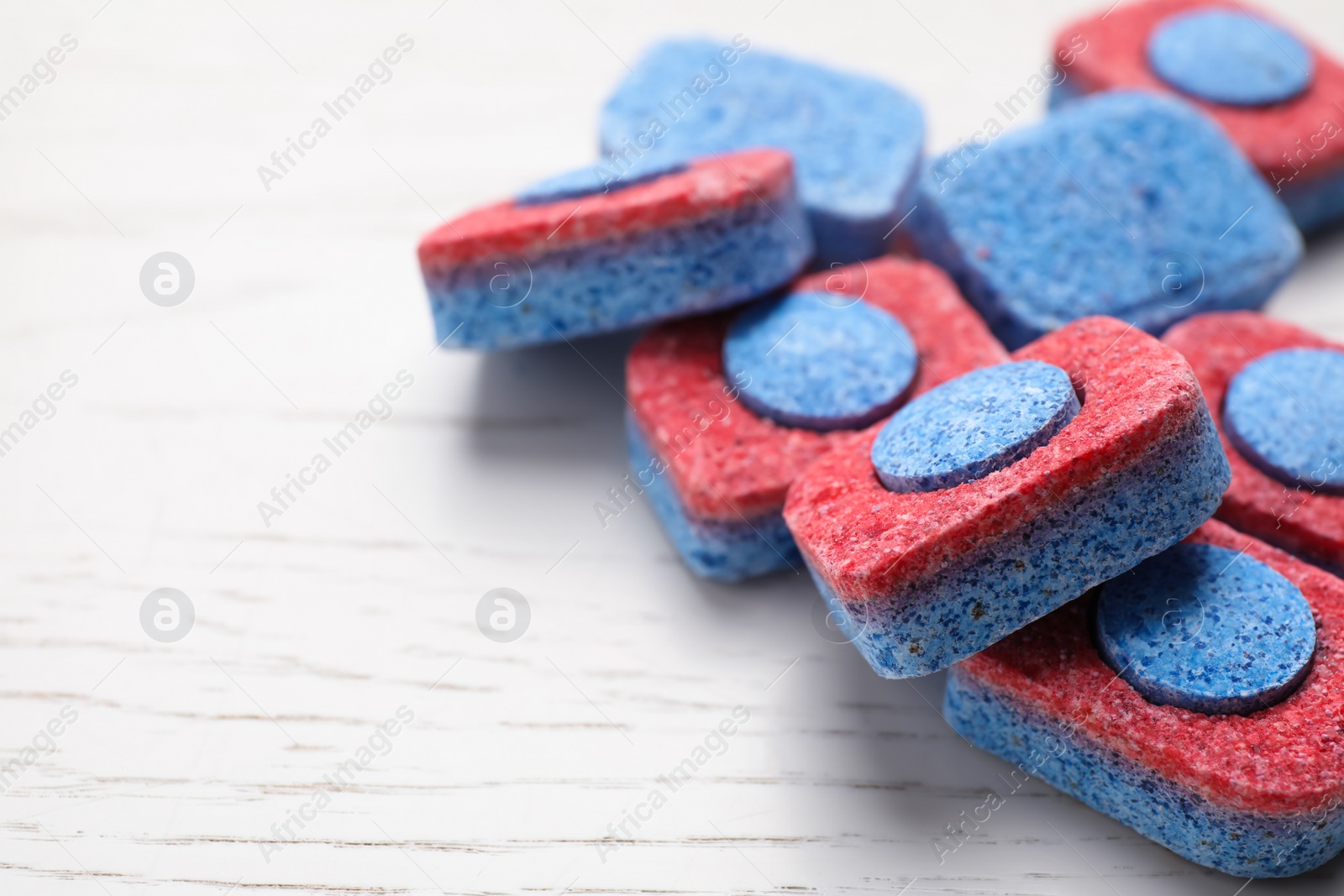 Photo of Many dishwasher detergent tablets on white wooden table, space for text