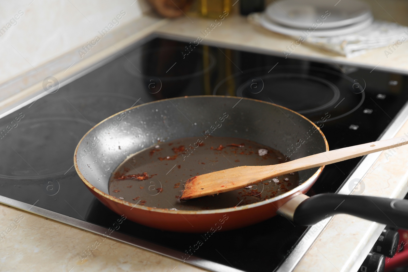 Photo of Frying pan with spatula and used cooking oil on stove