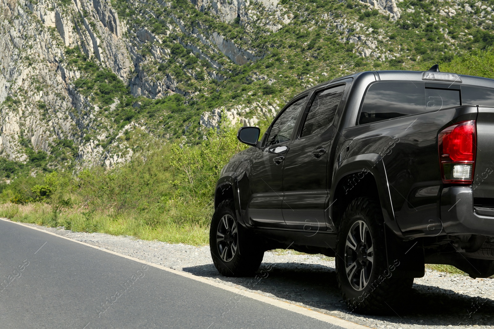 Photo of Picturesque view of big mountains and trees near road with black car, space for text