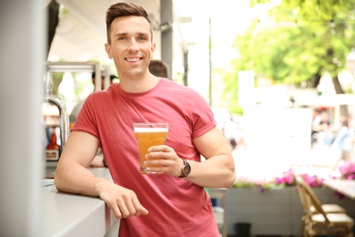 Photo of Young man with glass of cold beer near bar counter