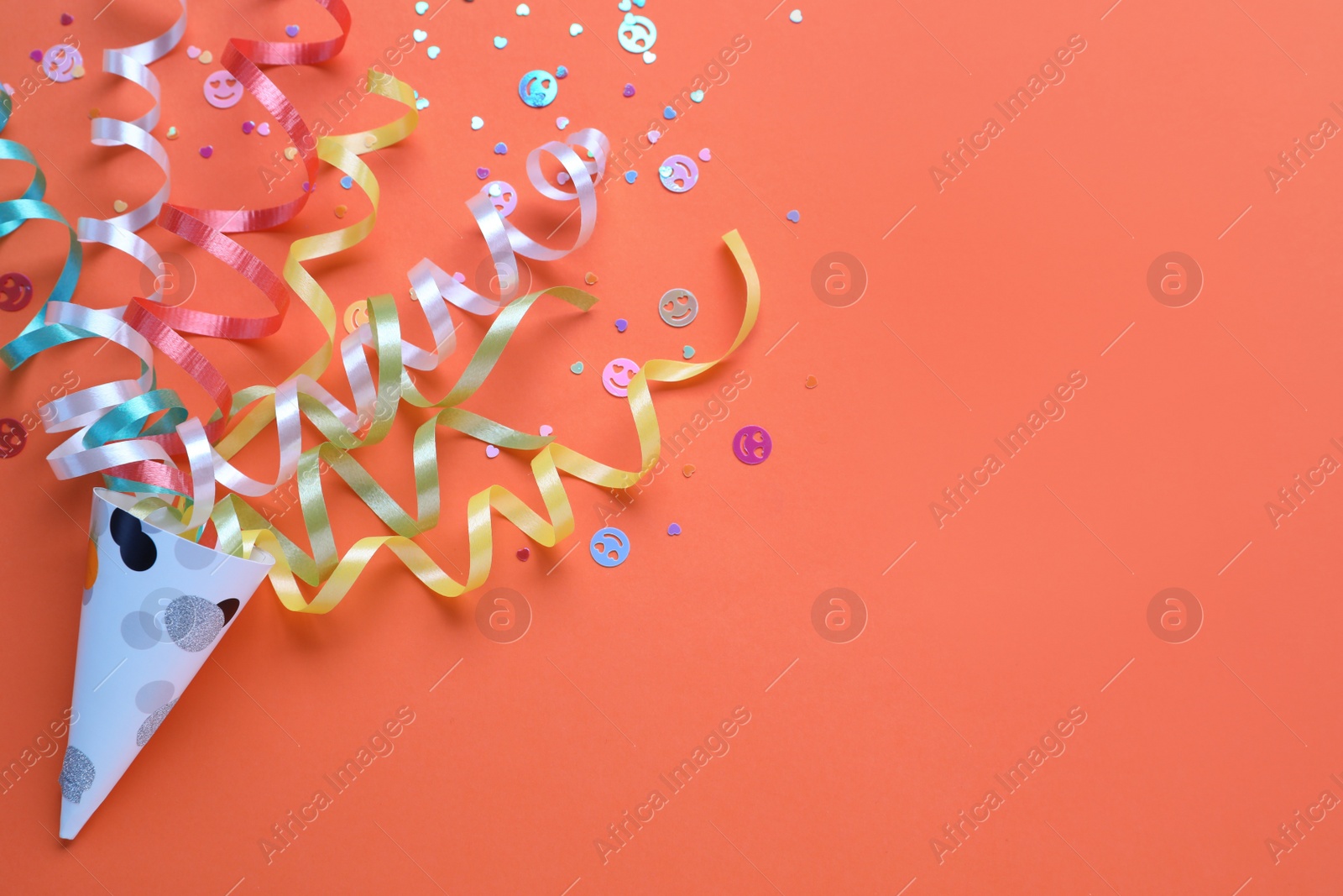 Photo of Colorful confetti and streamers with party cracker on orange background, top view. Space for text