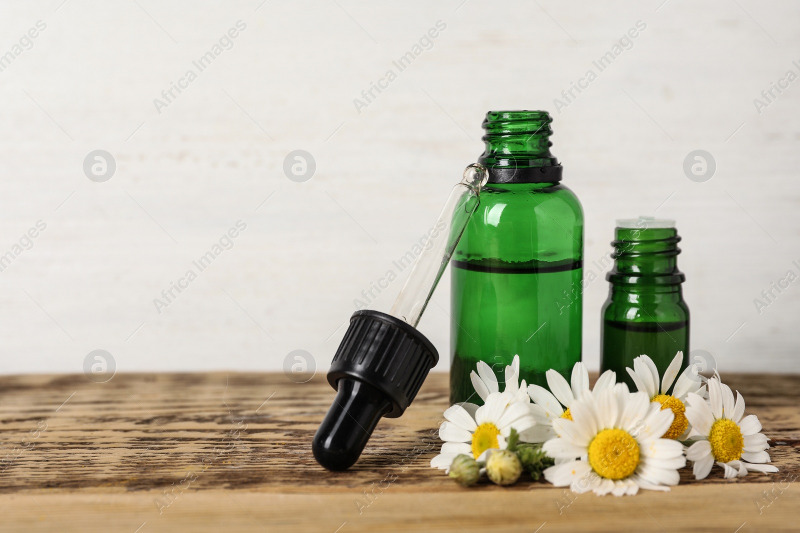 Photo of Composition with bottles of chamomile essential oil on table. Space for text