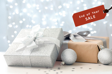 Image of Boxing day. Gifts and tag with text End Of Year Sale against blurred Christmas lights