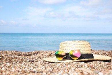 Straw hat and colorful heart shaped sunglasses on sea beach. Space for text