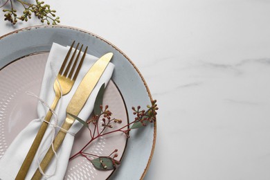 Photo of Stylish setting with cutlery and eucalyptus leaves on white marble table, flat lay. Space for text