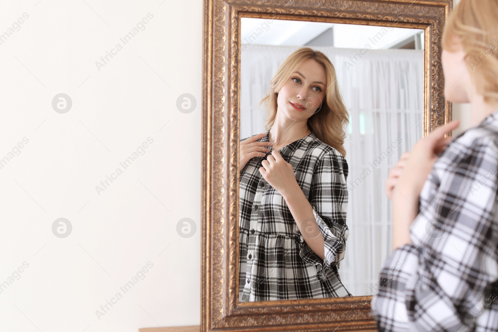 Photo of Young beautiful woman near mirror in makeup room