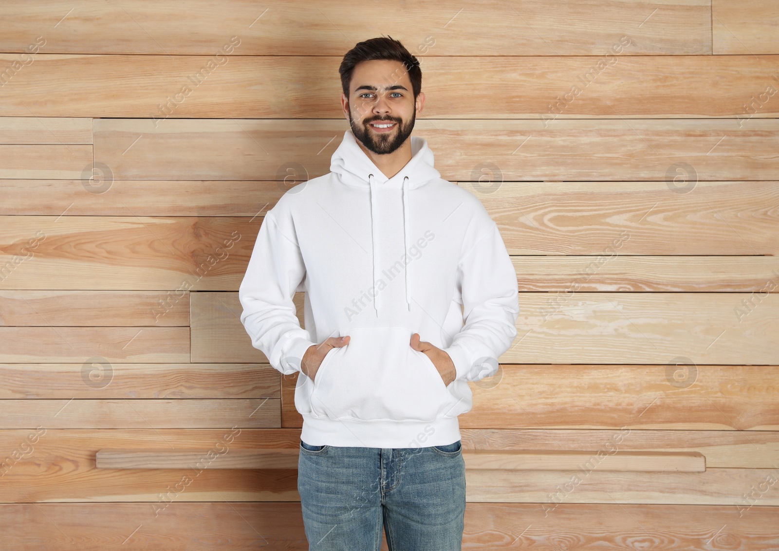 Photo of Portrait of young man in sweater at wooden wall. Mock up for design