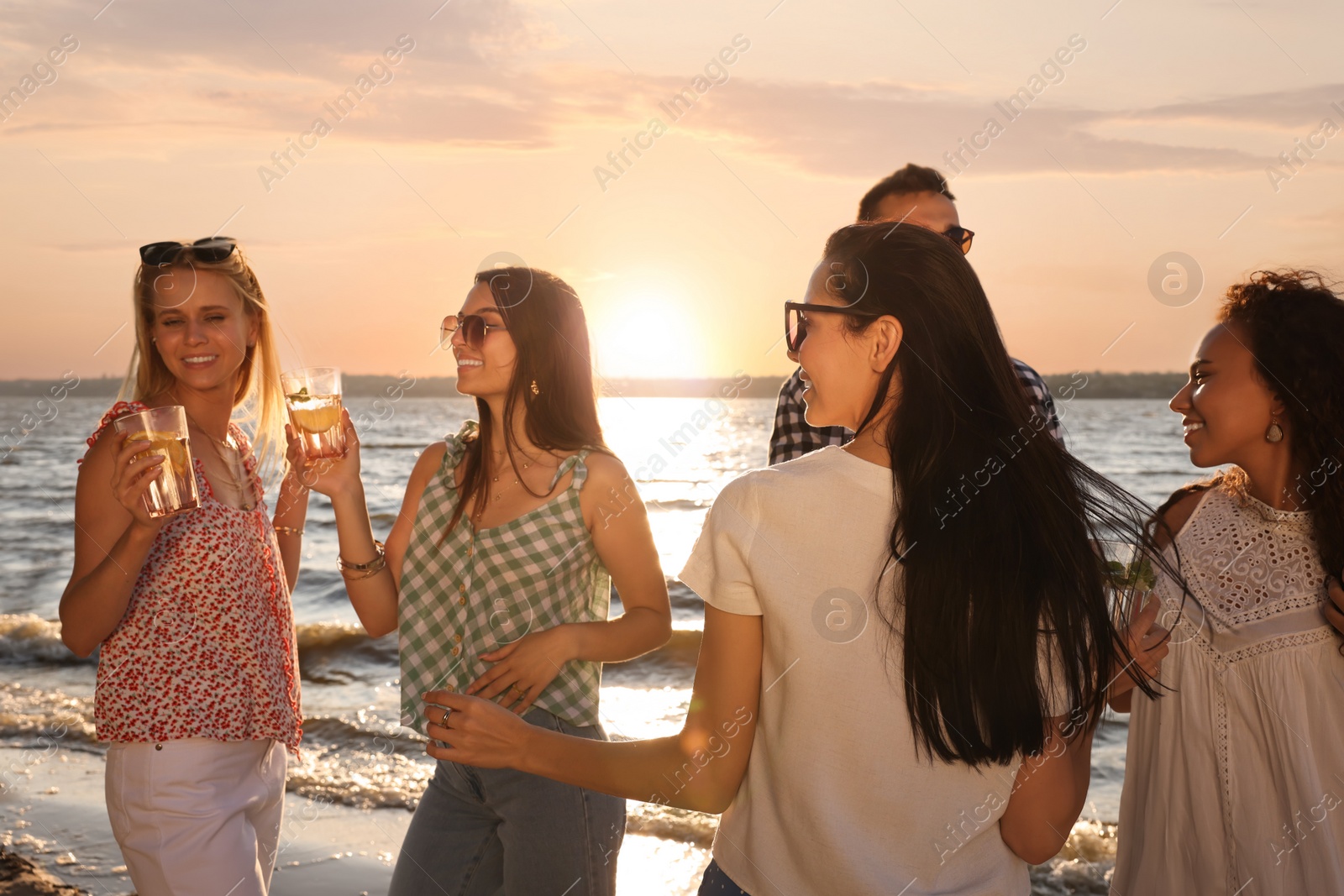 Photo of Group of friends with drinks having fun near river at summer party