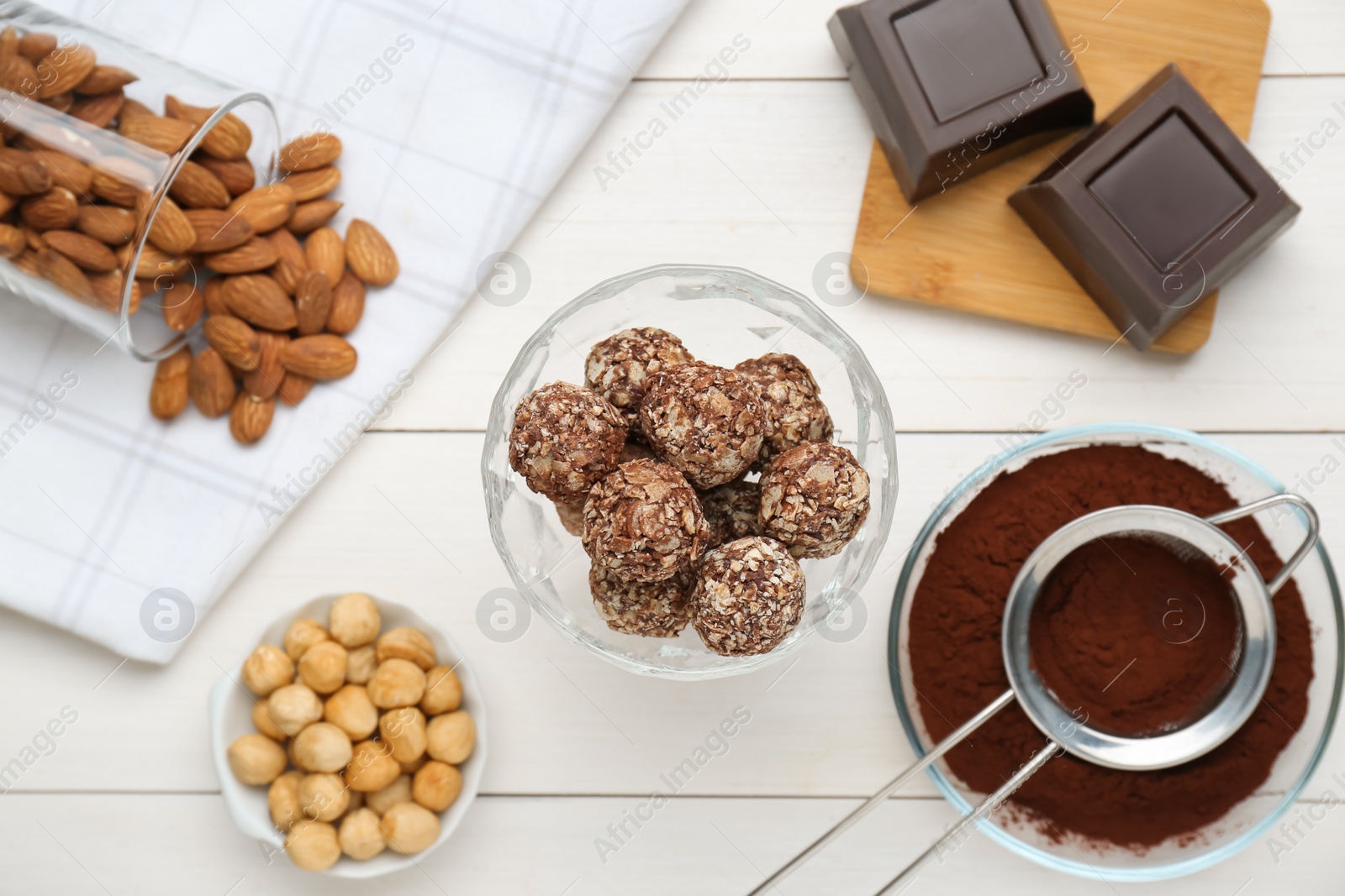 Photo of Tasty chocolate balls and ingredients on white wooden table, flat lay