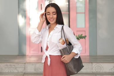 Photo of Young woman with leather shopper bag outdoors