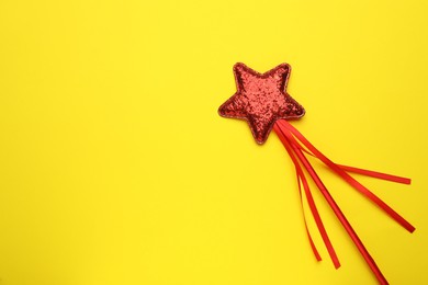 Beautiful red magic wand on yellow background, top view. Space for text