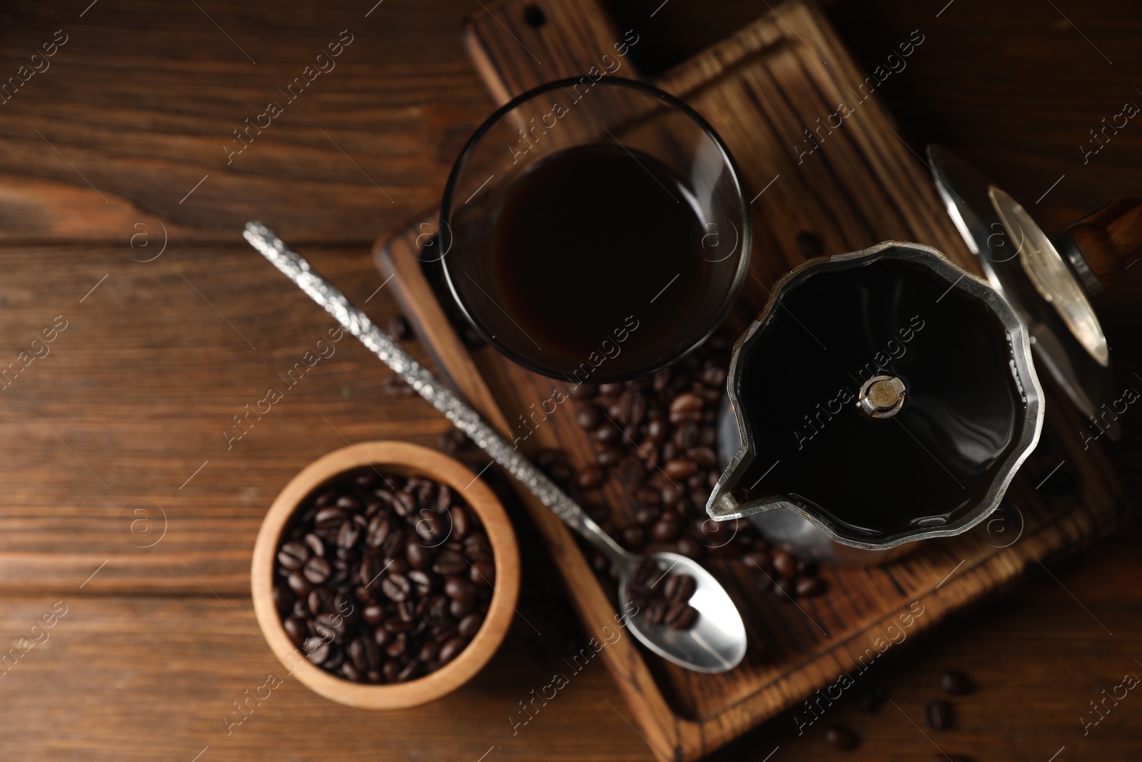 Photo of Brewed coffee, moka pot and beans on wooden table, flat lay