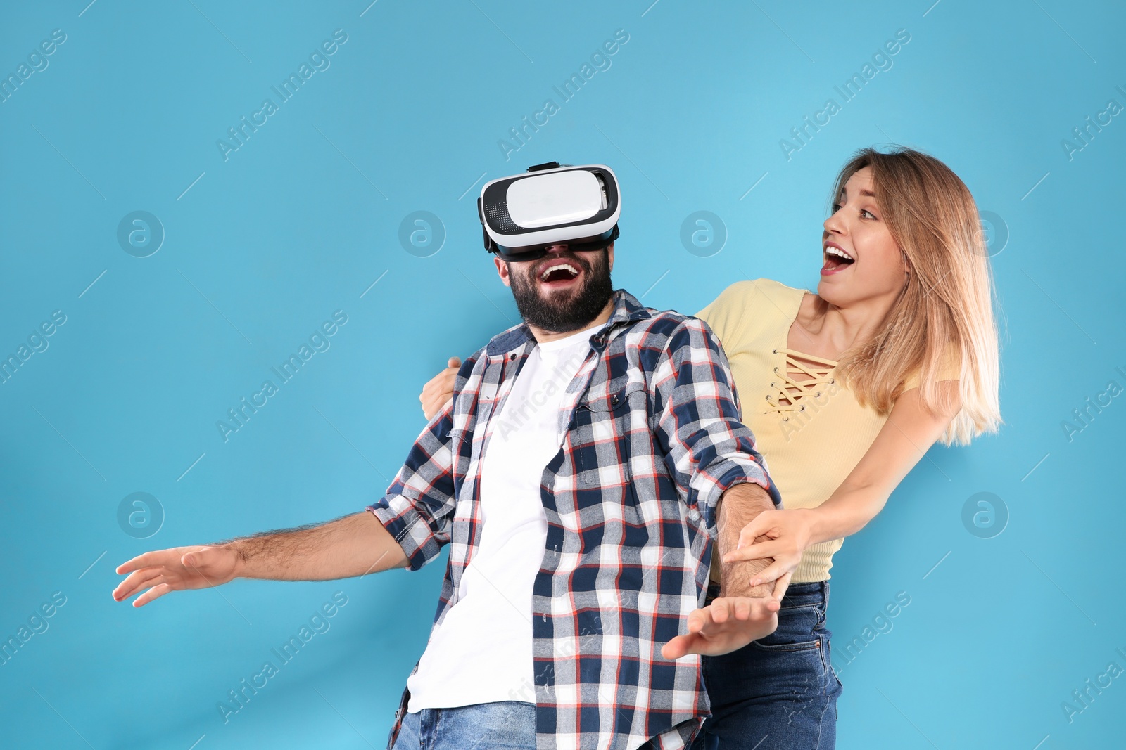 Photo of Young man playing video games with VR headset and emotional woman on color background