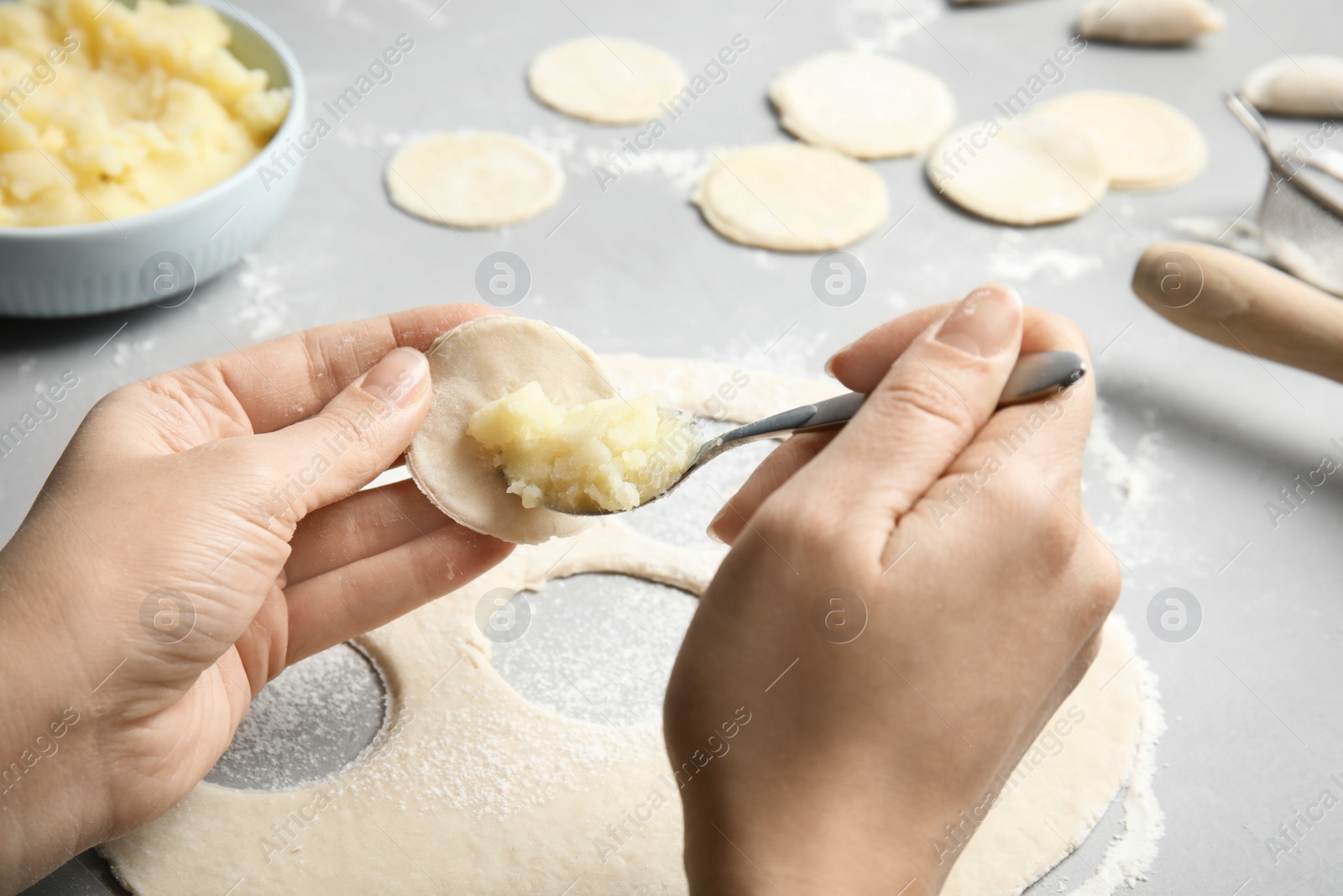 Photo of Woman cooking delicious dumplings over table, closeup