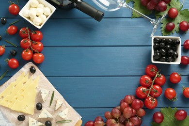 Photo of Frame of tasty red wine and snacks on blue wooden table, flat lay. Space for text