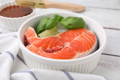 Fresh marinated fish and lime on white wooden table, closeup