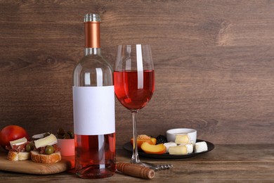 Delicious rose wine and snacks on wooden table, space for text
