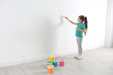 Little child painting on white wall indoors. Space for text