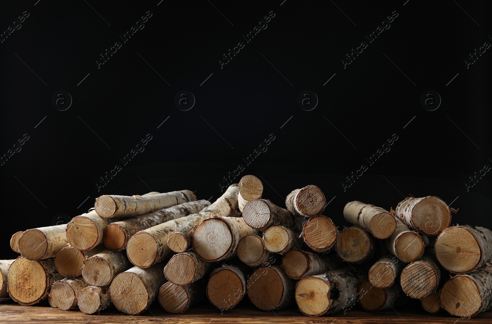 Photo of Cut firewood on table against black background