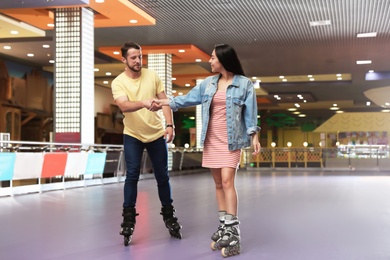 Photo of Young couple spending time at roller skating rink