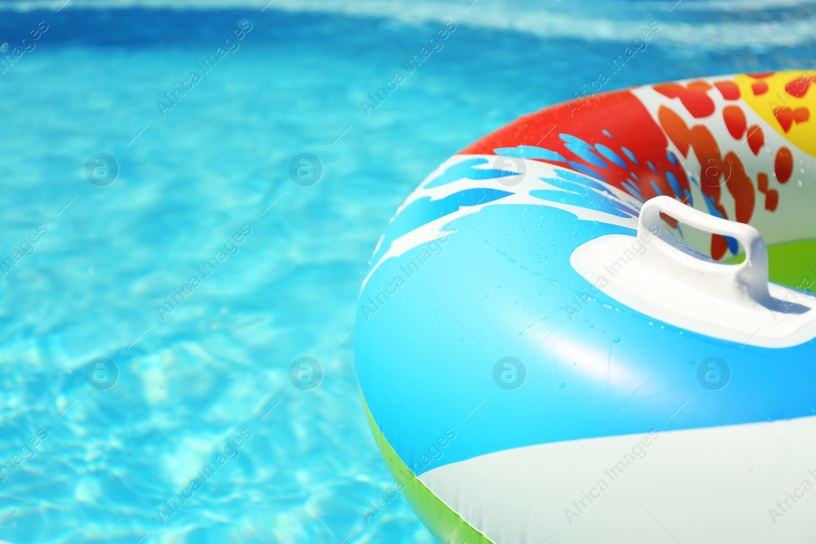 Photo of Colorful inflatable ring floating in swimming pool on sunny day, closeup. Space for text