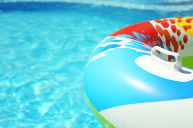 Colorful inflatable ring floating in swimming pool on sunny day, closeup. Space for text