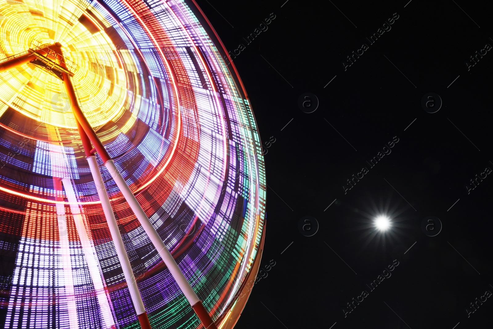 Photo of Beautiful glowing Ferris wheel against dark sky, low angle view. Space for text