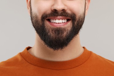 Photo of Man with clean teeth smiling on gray background, closeup