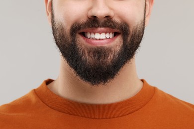 Man with clean teeth smiling on gray background, closeup