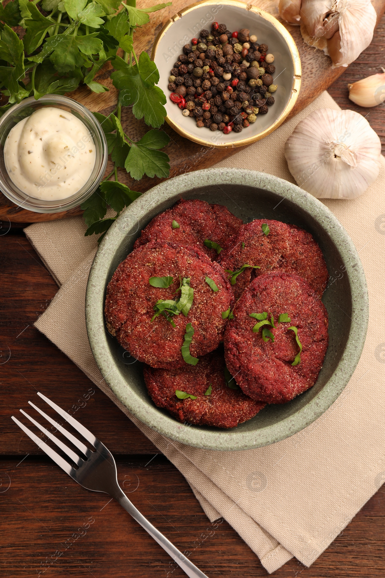 Photo of Tasty vegan cutlets with sauce and ingredients on wooden table, flat lay