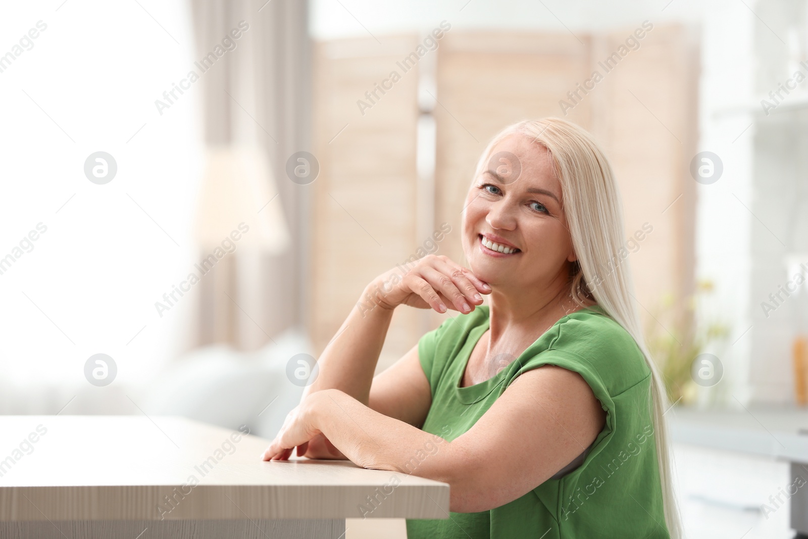 Photo of Portrait of happy mature woman at table indoors